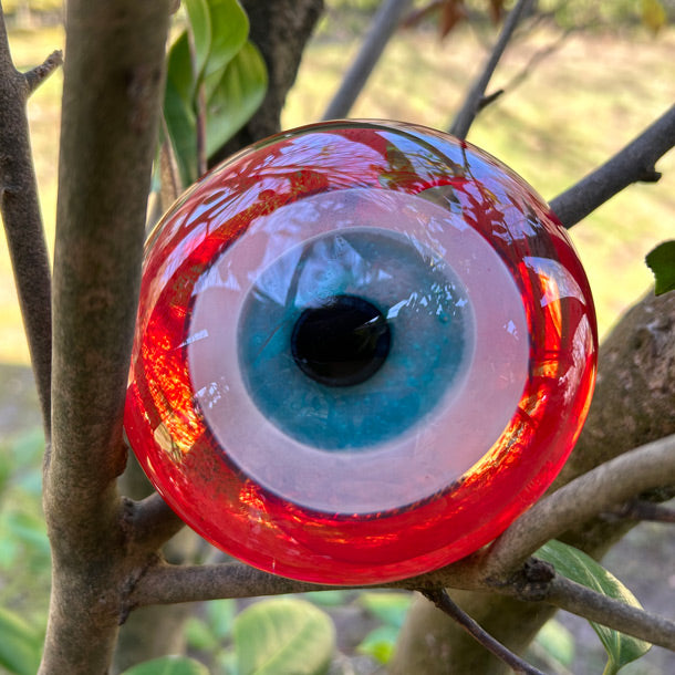 Agac dallarinin arasinda kirmizi goz nazarlik_Red evil eye bead among the tree branches