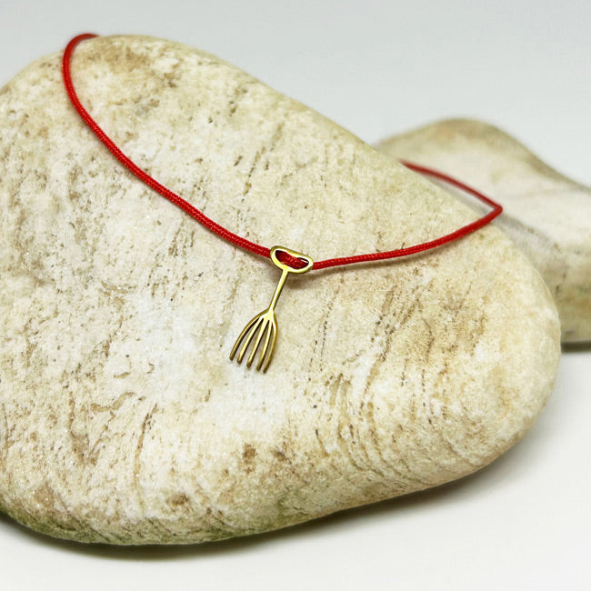 Bej tas ustunde duran el parmak tarak motifli kirmizi ipli bileklik_Red string bracelet with hand finger and comb motif on a beige stone