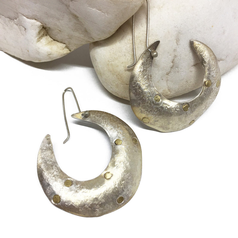 Beyaz tasin yaninda hilal seklinde bir cift gumus kupe_A pair of crescent shaped silver earrings