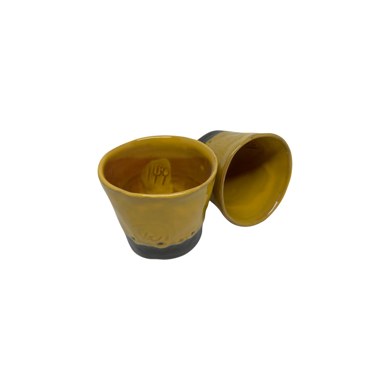 Biri dik digeri yan duran iki adet sari seramik bardak_Two yellow ceramic cups one standing upright and the other sideways