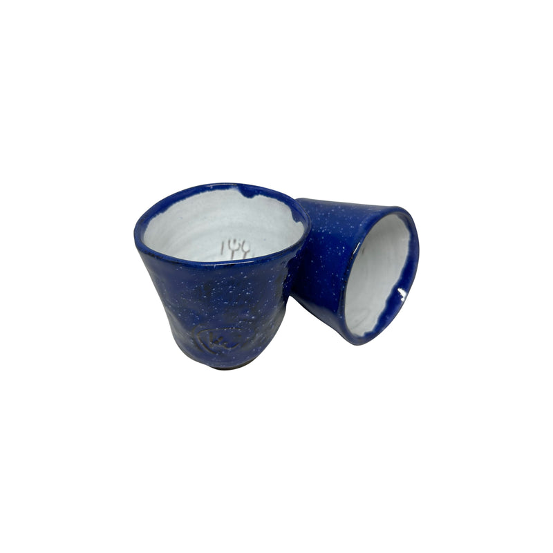 Biri yan duran iki tane lacivert beyaz seramik bardak_Two dark blue and white ceramic cups one of which is ranked