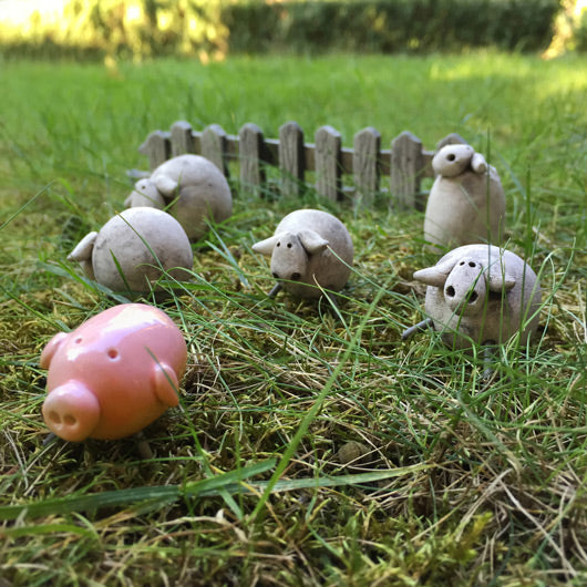 Cimdeki citin onunde duran pembe seramik domuz ve gri koyunlar_Small pink ceramic piggy and grey sheep in front of the fence on the grass