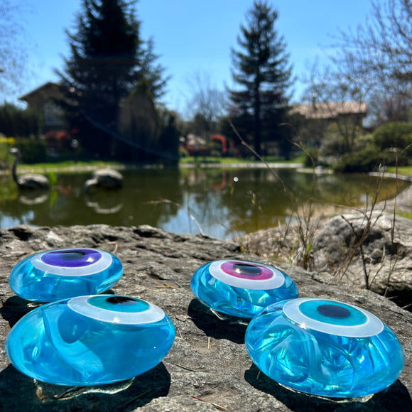 Golet kenarinda acik turkuaz cam nazarliklar_Light turquoise glass amulets beside the pond