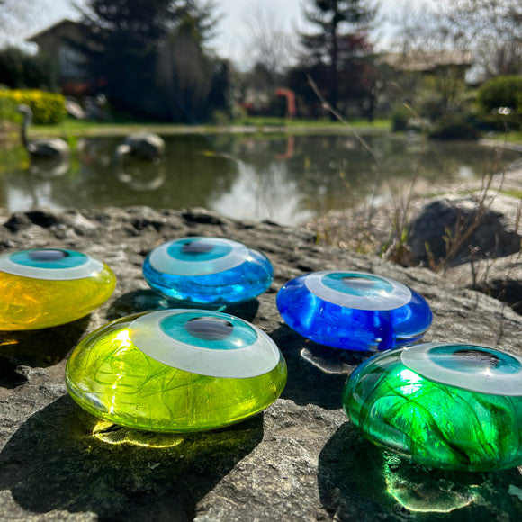 Golet yaninda degrade renklerde cam nazarliklar_Glass amulets beside the pond