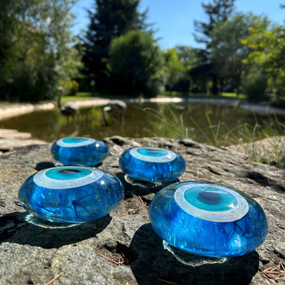 Golet yaninda kayada duran dort tane lacivertli turkuaz nazarlik_Four turquoise evil eye beads beside the pond