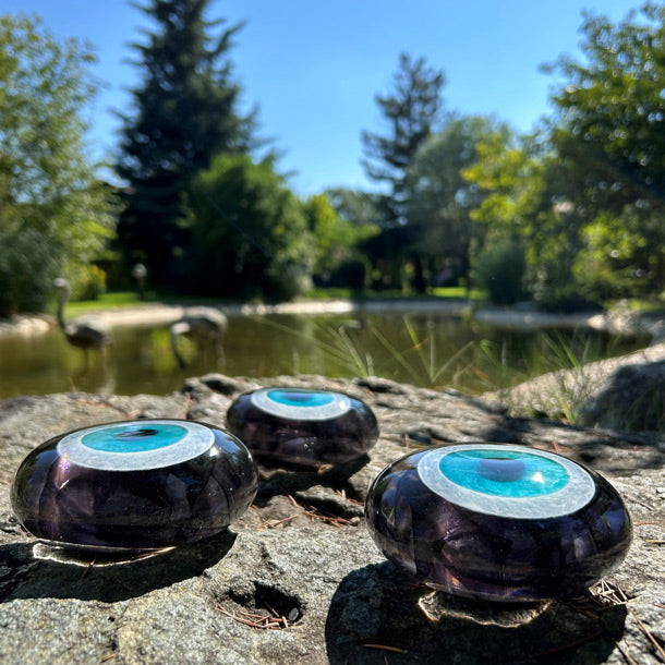 Golet yaninda turkuaz fume uc nazarlik_Three smoke grey clear glass evil eye beads beside the pond