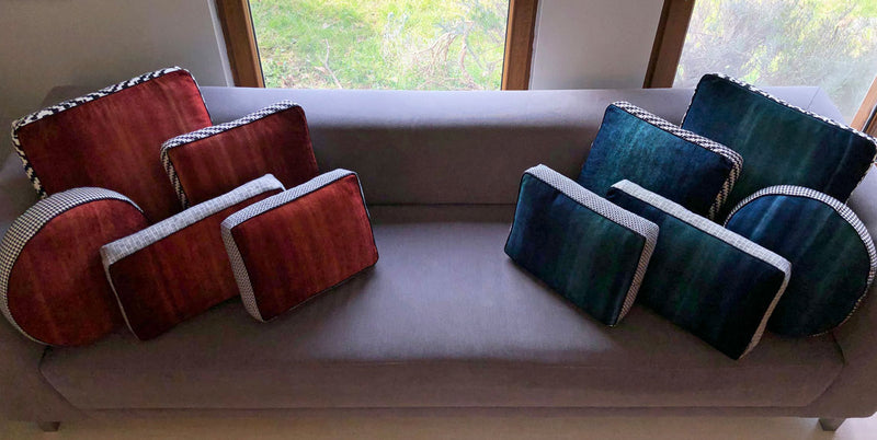 Gri kanepenin saginda ve solunda kizil ve turkuaz yastik setleri_Reddish brown and peacock blue cushion sets on the corners of a grey sofa