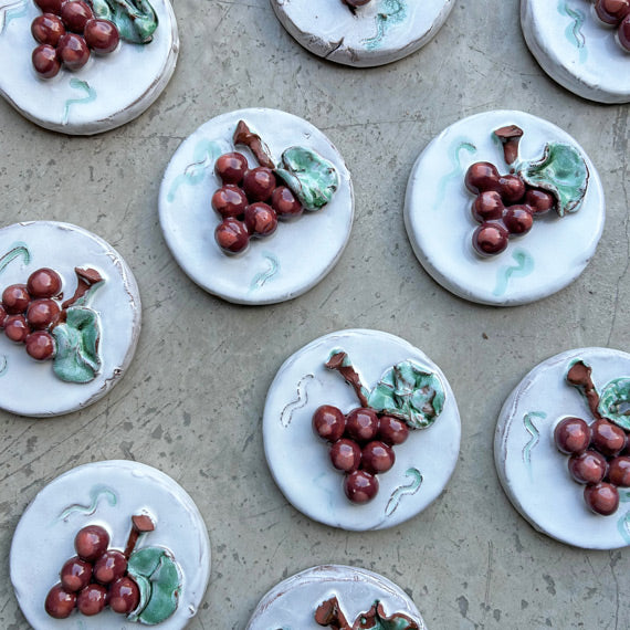 Gri zeminde kirmizi uzum kabartmali beyaz dairesel seramik susler_White circular ceramic ornaments embossed with red grapes