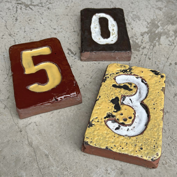 Gri zeminde uc adet uzerleri rakamli seramik kagit agirliklari_Three ceramic paper weights with numbers 0 5 and 3 on them