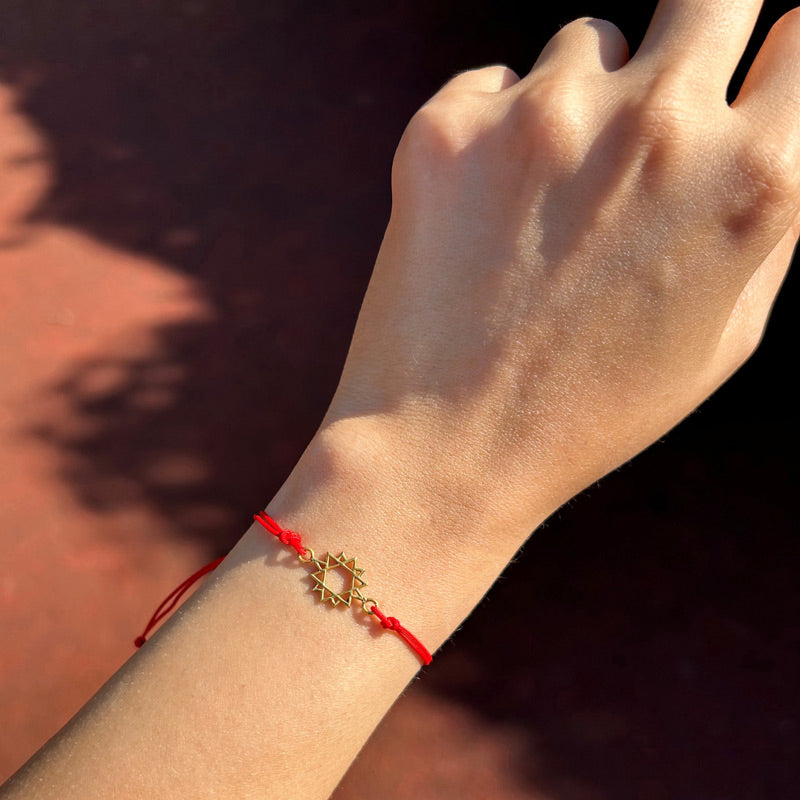 Gunesteki kadin kolunda altin kaplama yildizli kirmizi ipli bileklik_Red string bracelet with eight pointed star on woman arm
