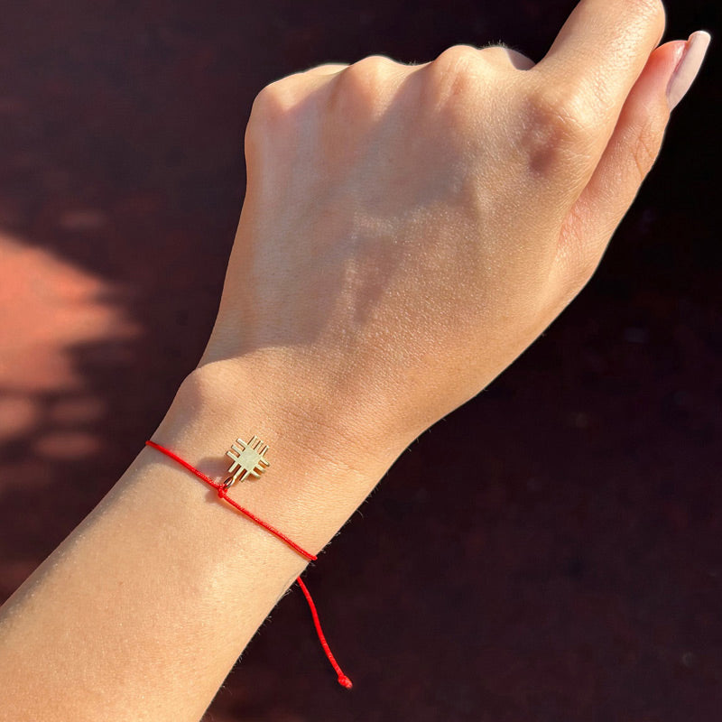 Kadin bileginde kirmizi ipli altin kaplama Anadolu Motifli tasarim bileklik_Red string gold plated Anatolian Motif bracelet on a woman s wrist