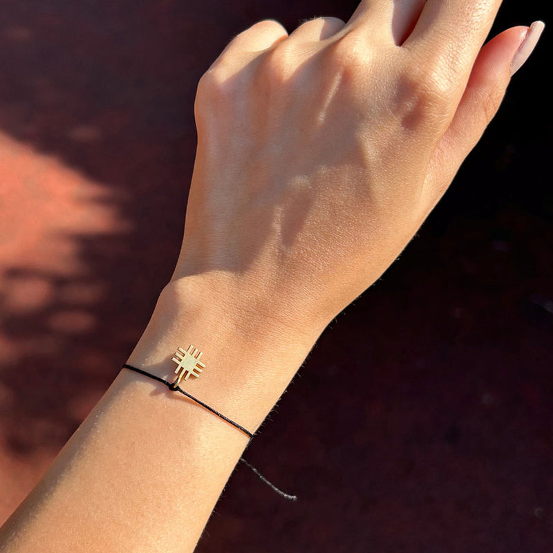 Kadin bileginde siyah ipli altin kaplama Anadolu Motifli tasarim bileklik_Black string gold plated Anatolian Motif bracelet on a woman s wrist