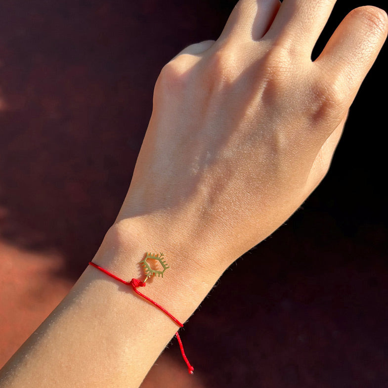 Kola takilmis Anadolu Motiflerinden pitrak motifli kirmizi ipli bileklik_Red string bracelet with burdock motif among Anatolian Motifs on woman arm