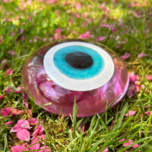 Pembe cicekler dokulmus cimlerde pembe cam nazarlik_Pink evil eye glass bead on the lawn