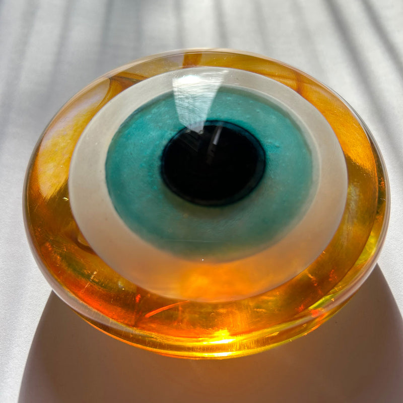 Perspektif golgede kehribar rengi goz boncugu_Amber colored glass evil eye bead in the shade