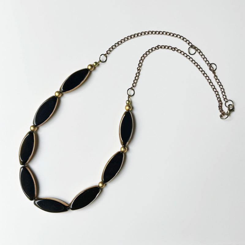Sekiz adet altinli syah mekik seklinde boncuktan olusan kolye_Necklace composed of eight shuttle shaped golded black beads