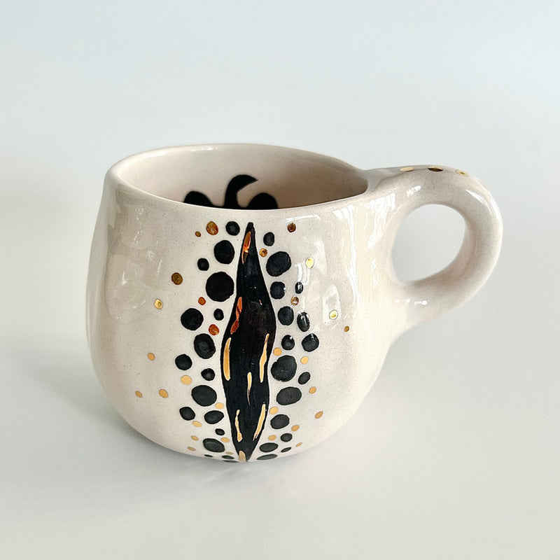 Siyah ve altin rengi benekli desenleri olan beyaz kupa_White mug with black and gold color patterns