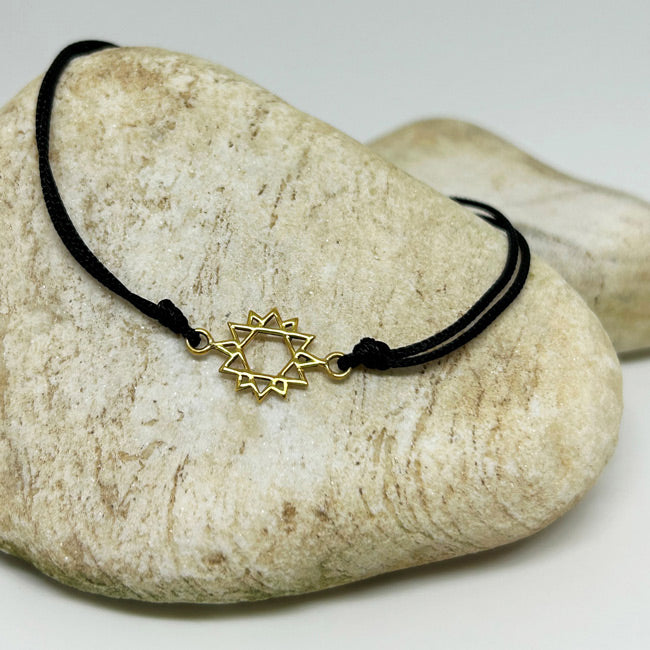 Tas ustunde duran altin kaplama on iki koseli yildiz motifli siyah ipli bileklik_Black string bracelet with a gold-plated twelve-pointed star motif on a stone