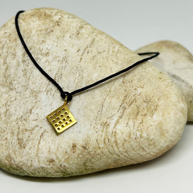 Tas ustunde duran bereket sembolu Anadolu Motifli siyah ipli bileklik_Black string bracelet with Anatolian Motif symbolizing fertility on a stone