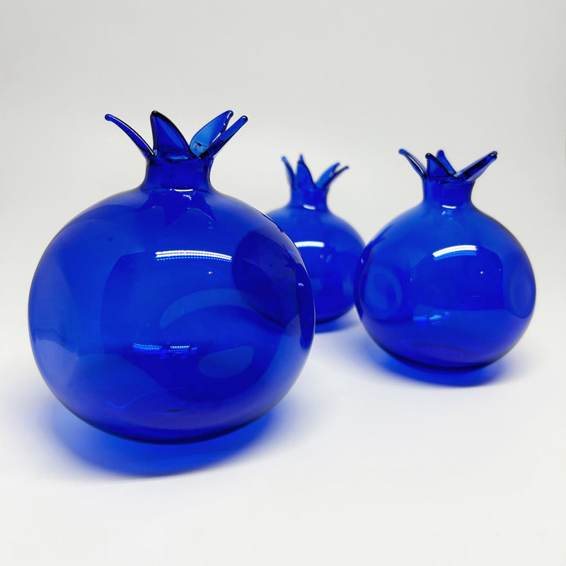 Yan yana dizilmis irili ufakli uc adet gece mavisi nar_Three dark blue pomegranates in various sizes arranged side by side