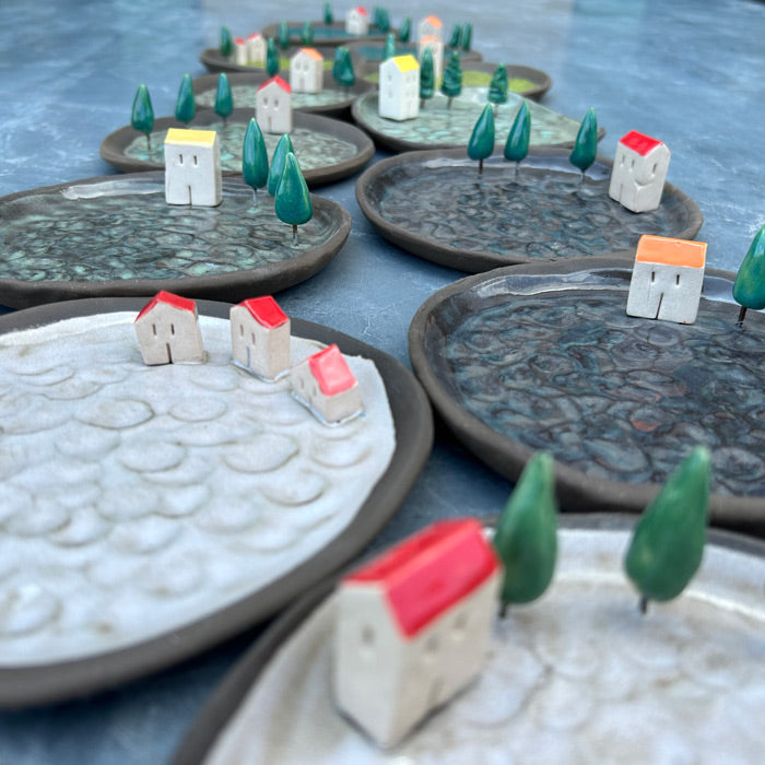 Yan yana ve ardarda siralanmis ustunde ev ve agaclar olan seramik tabaklar_Ceramic plates with ornaments in a row and next to each other