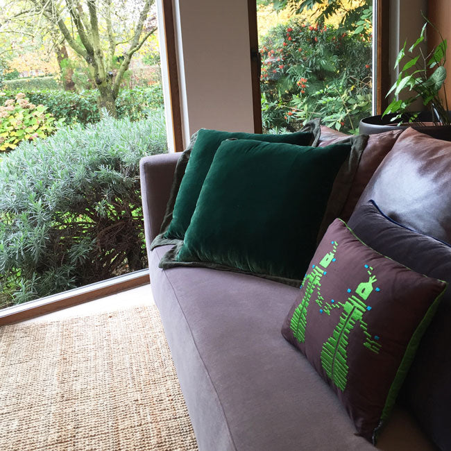 Bahceye bakan kanepede yesil ipek kadife kirlentler ve yesil insan motifli kahverengi ipek yastik_Green silk velvet cushions and green human motif embroidered brown silk pillow on a sofa