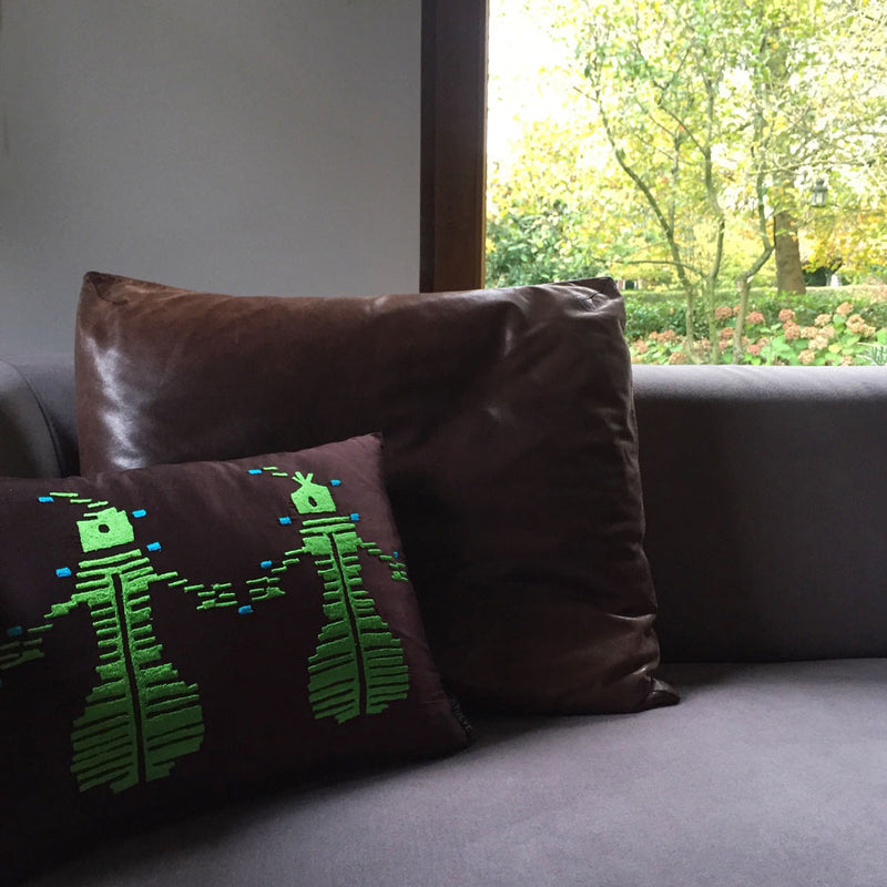 Bahceye bakan pencerenin onundeki gri koltukta yesil nakisli koyu kahverengi kirlentler_Dark brown pillows on a grey sofa in front of the window_kissen_coussin