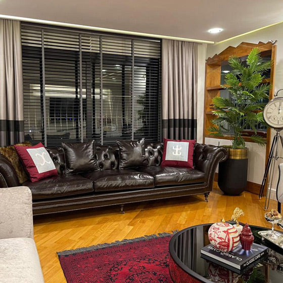 Bir Adana evindeki siyah deri kanepede bordo yastiklar_Burgundy colored silk cushions on a black leather sofa in a living room