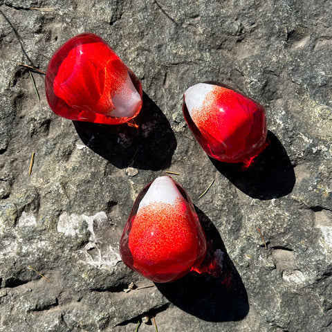 Gri kayanin ustunde uc adet kirmizi cam nar tanesi_Three red glass pomegrante seeds on the gray rock