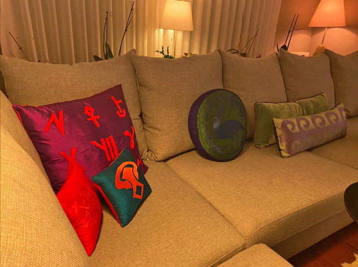 Los salondaki gri kanepede canli ve pastel renklerde yastiklar_Vibrant and pastel colored cushions on the grey sofa in softly illuminated living room