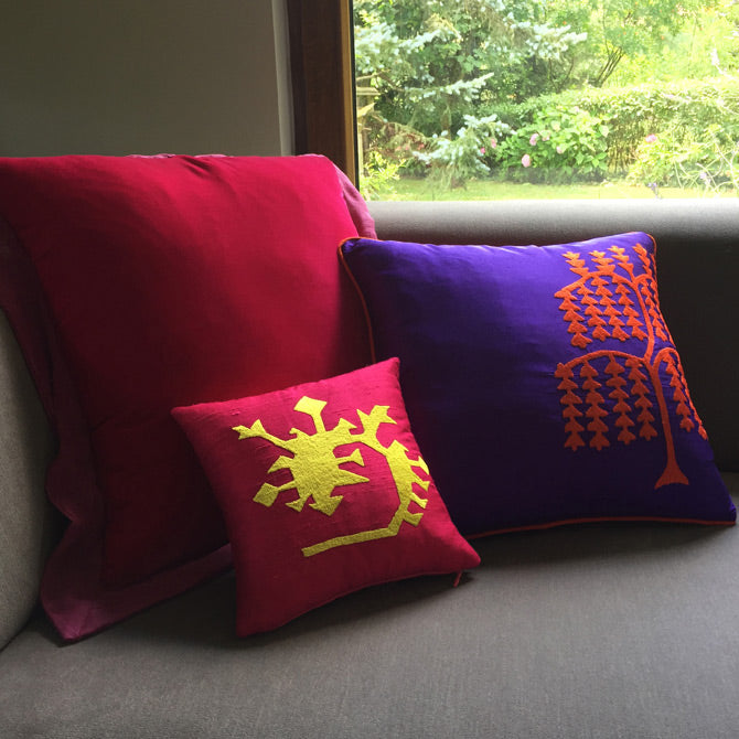 Pencerenin onundeki gri kanepede cingene pembesi sari ve mor nakisli ipek ve ipek kadife kirlentler_Purple yellow and magenta patterned silk and silk velvet cushions on the gray sofa by the window