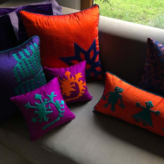 Pencerenin onundeki gri kanepede turuncu mor desenli ipek dekoratif yastiklar_Orange purple embroidered silk cushions on the grey sofa in front of the window