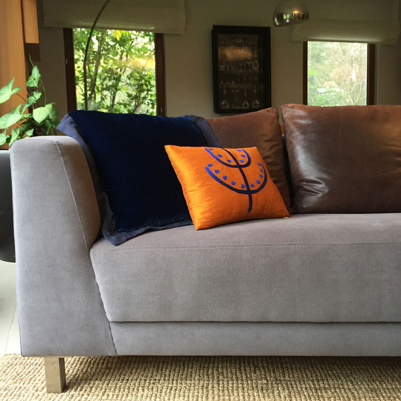 Gri kanepenin kosesinde lacivert ipek kadife ve el motifli turuncu ipek yastik_Navy blue silk velvet and orange silk cushion with hand motif at the corner of the grey sofa