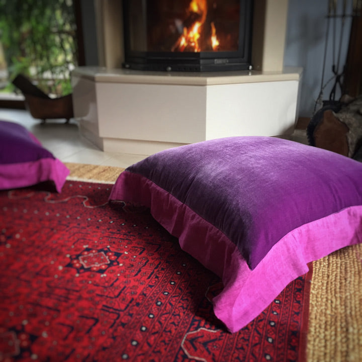 Sominenin onundeki bordo Afgan halisinin ustunde fusya mor ipek kadife yer yastigi_Fuchsia purple silk velvet floor pillow on a dark red Afghan carpet in front of the fireplace