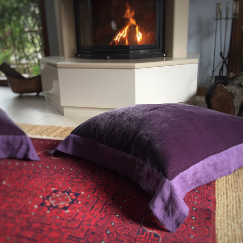 Sominenin onundeki bordo Afgan halisinin ustunde mor ipek kadife yer yastigi_Purple silk velvet floor pillow on a dark red Afghan carpet in front of the fireplace
