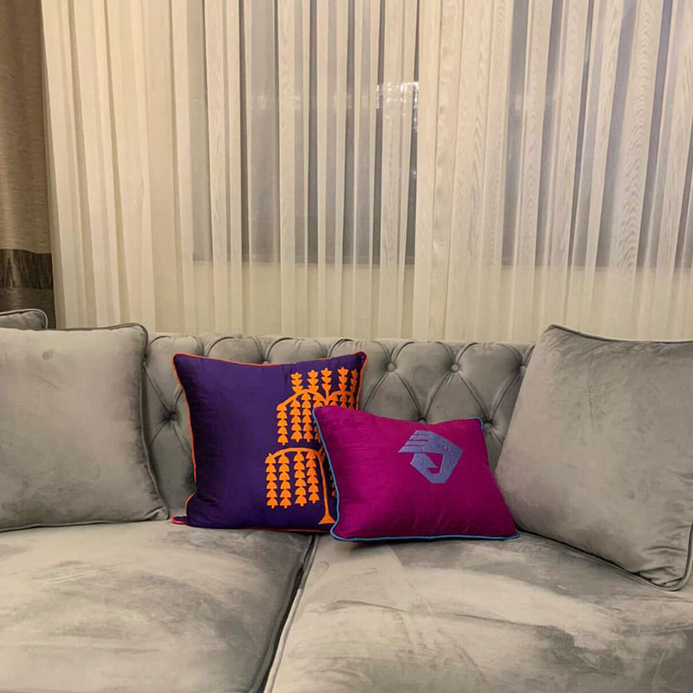 Tul perdenin onundeki gri kanepede turuncu mor yastiklar_Orange and purple cushions on the grey sofa in front of the curtain
